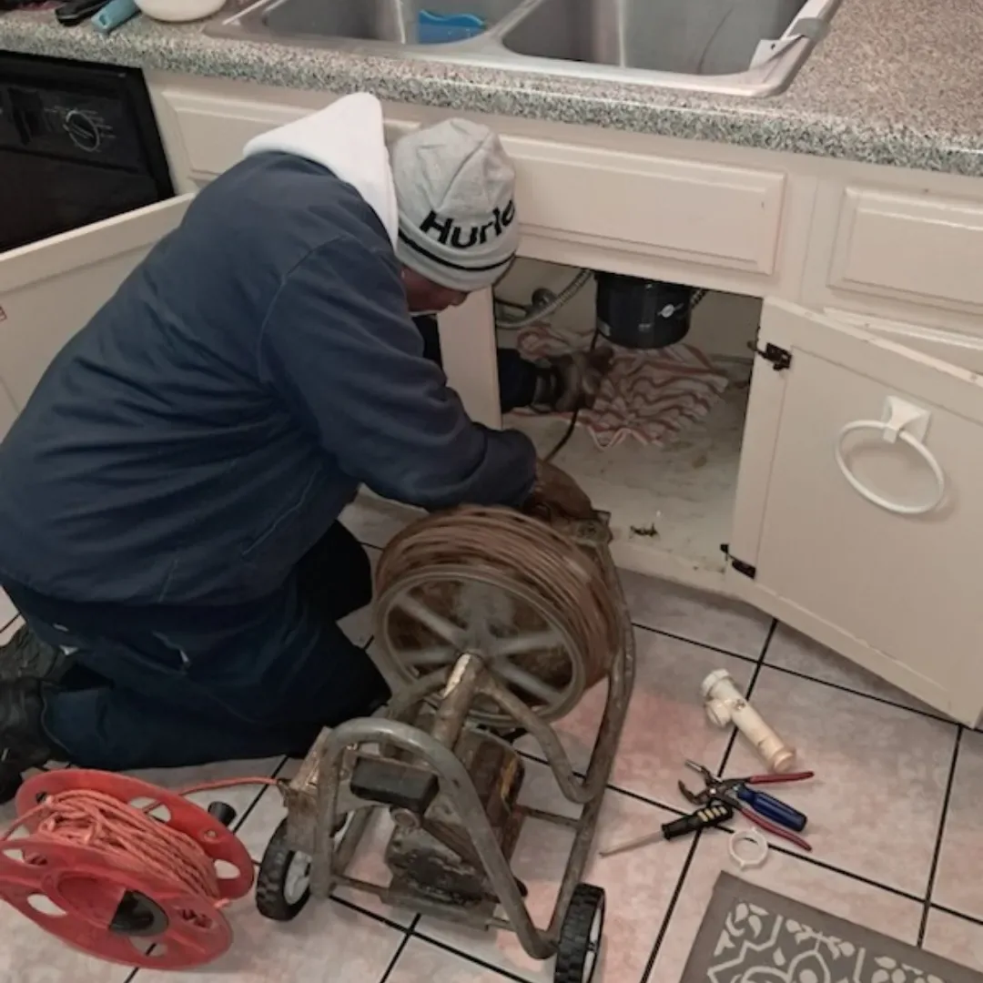 D3 Drain Cleaning technician running a drum machine on a sink drain line