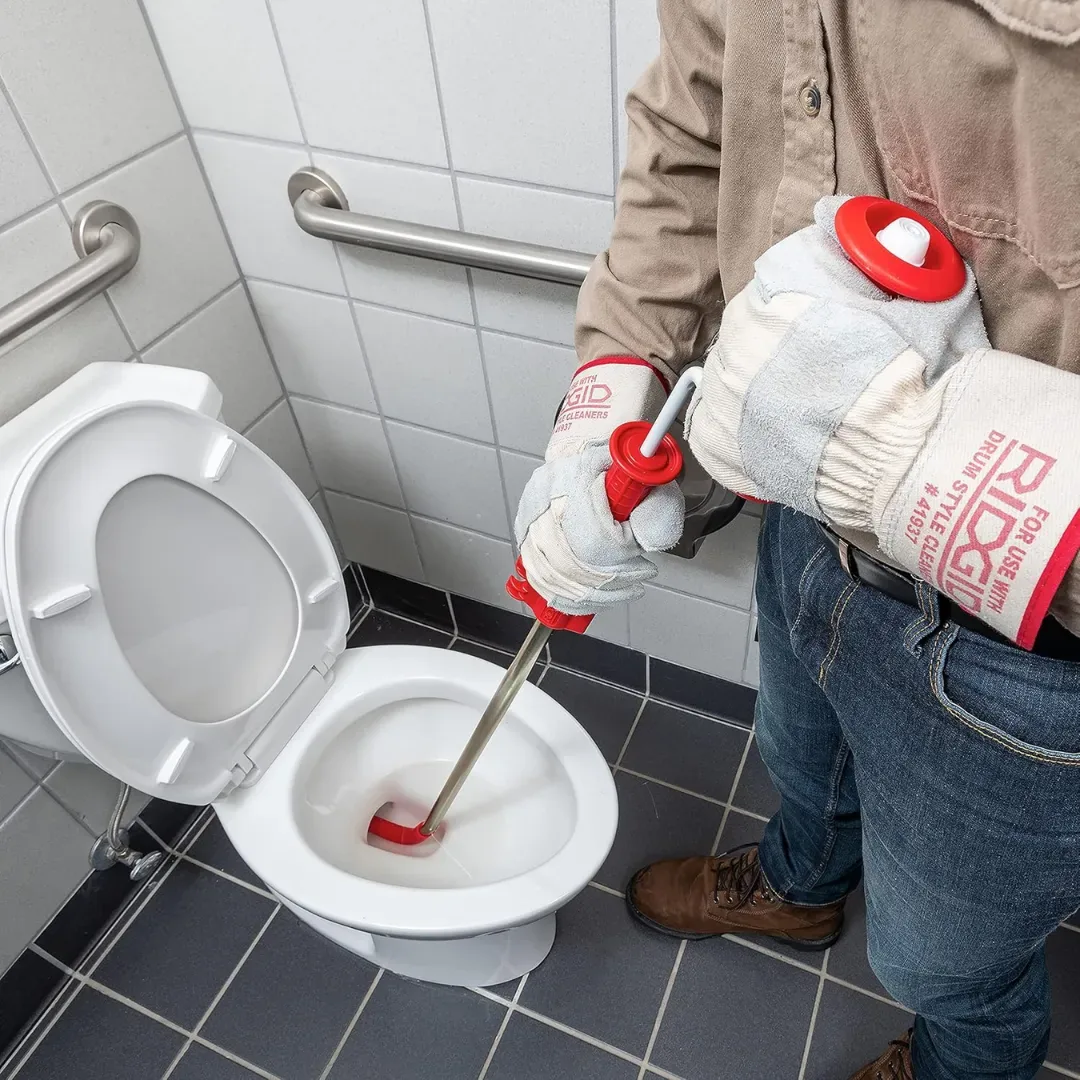 Technician using a closet auger to clear a blocked toilet